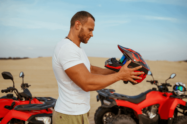 Man holding a motorcycle helmet outdoors.