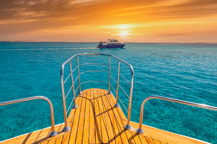 Boat sailing on clear blue water at sunset
