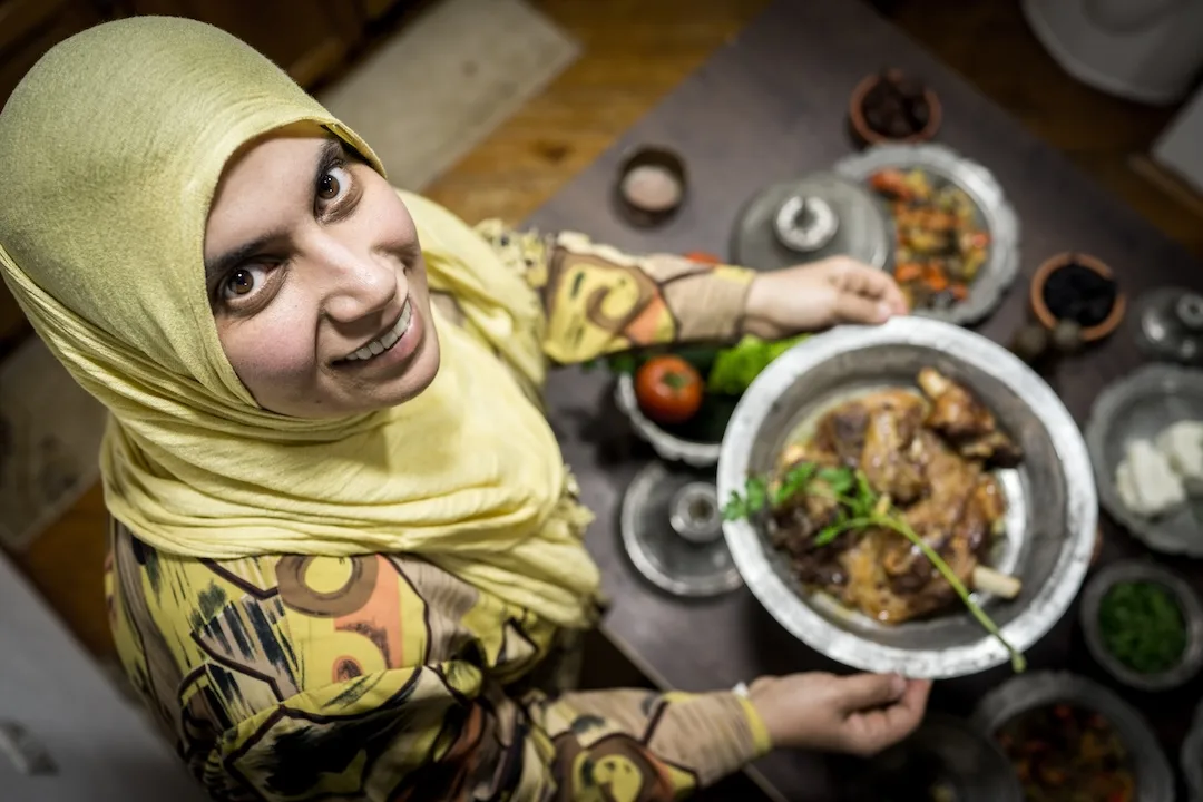 Smiling woman presenting a dish in kitchen