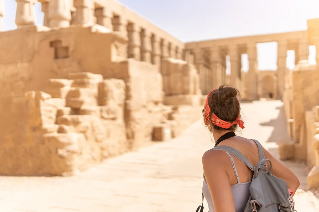 Woman exploring ancient ruins in sunlight.