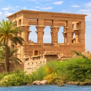 Ancient stone temple surrounded by greenery and water.
