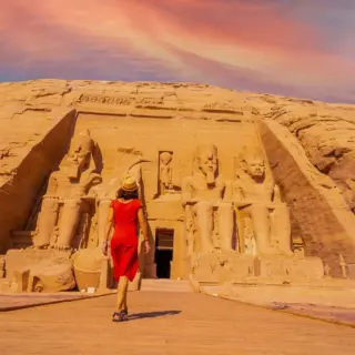 A young tourist girl in red dress walking towards the Abu Simbel Temple