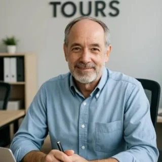 Smiling man at desk with laptop and documents