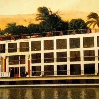 Cruise ship on a river surrounded by palm trees.