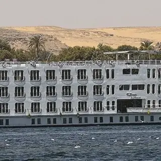 Large white cruise ship on calm river.