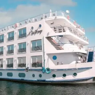 White cruise ship docked by the river.