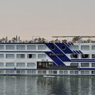 Cruise ship sailing on a river surrounded by greenery.