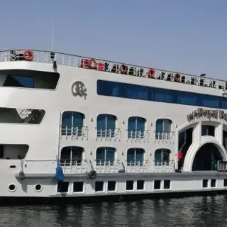 Cruise ship on a calm river with sandy hill.
