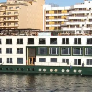 Large riverboat docked near urban buildings.